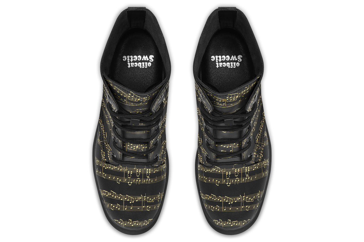 Black boots with a black sole, featuring yellowish/gold sheet music design.