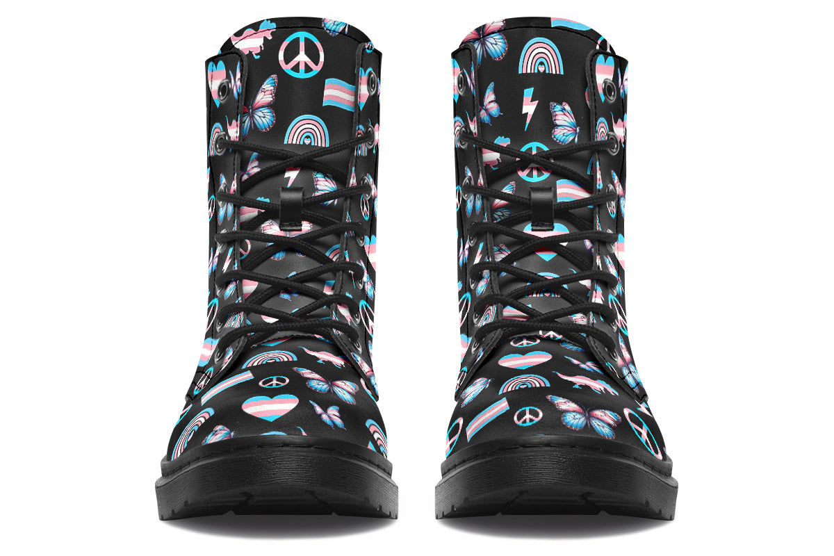 Black boots featuring a pattern of various icons in the trans flag colours, such as hearts, rainbows, peace signs, flags, butterflies and dinosaurs.