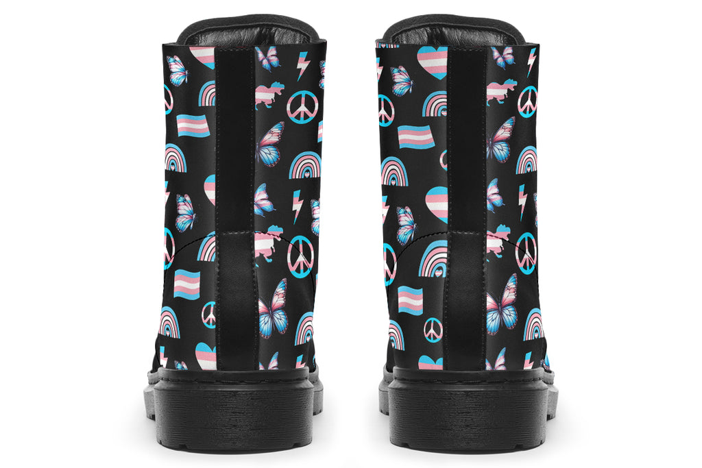 Black boots featuring a pattern of various icons in the trans flag colours, such as hearts, rainbows, peace signs, flags, butterflies and dinosaurs.