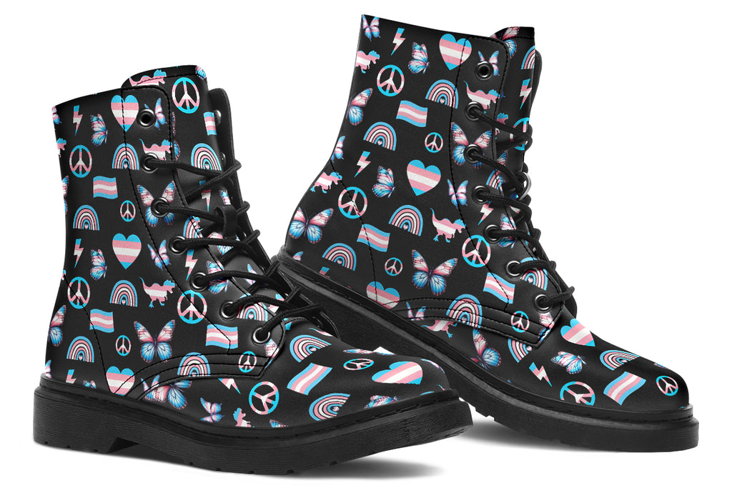 Black boots featuring a pattern of various icons in the trans flag colours, such as hearts, rainbows, peace signs, flags, butterflies and dinosaurs.