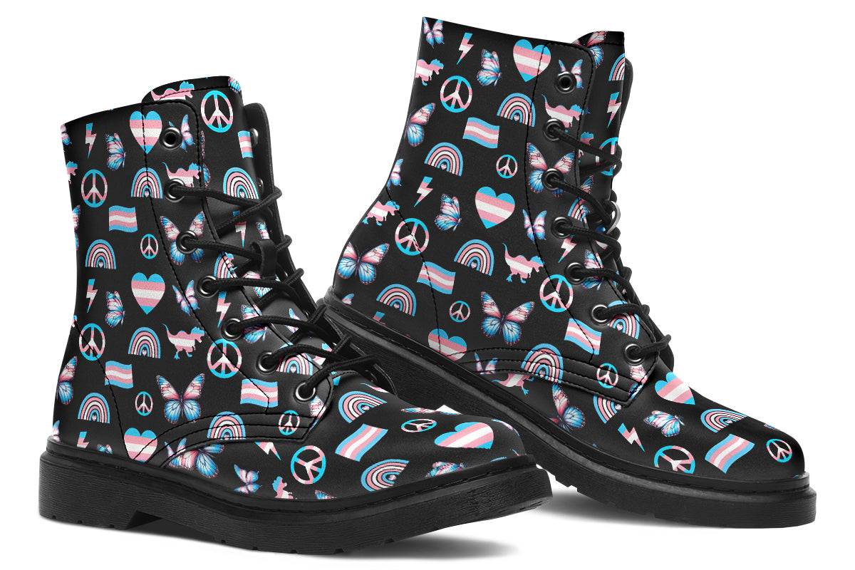 Black boots featuring a pattern of various icons in the trans flag colours, such as hearts, rainbows, peace signs, flags, butterflies and dinosaurs.
