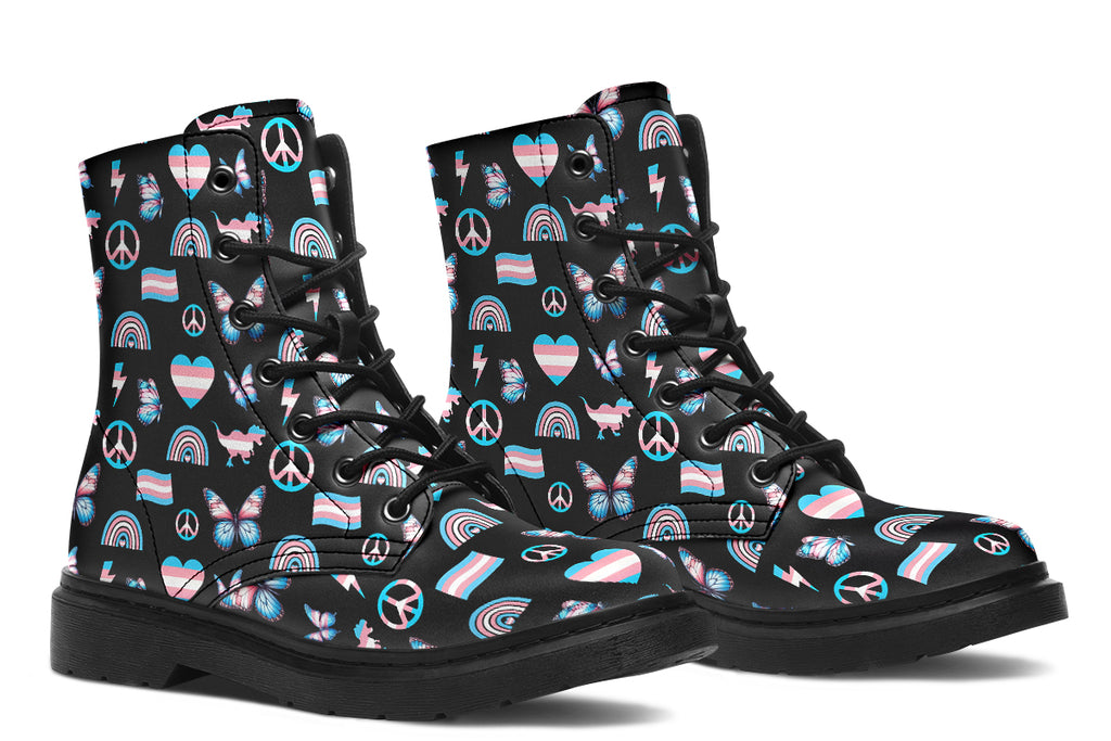 Black boots featuring a pattern of various icons in the trans flag colours, such as hearts, rainbows, peace signs, flags, butterflies and dinosaurs.