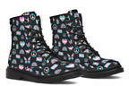 Black boots featuring a pattern of various icons in the trans flag colours, such as hearts, rainbows, peace signs, flags, butterflies and dinosaurs.