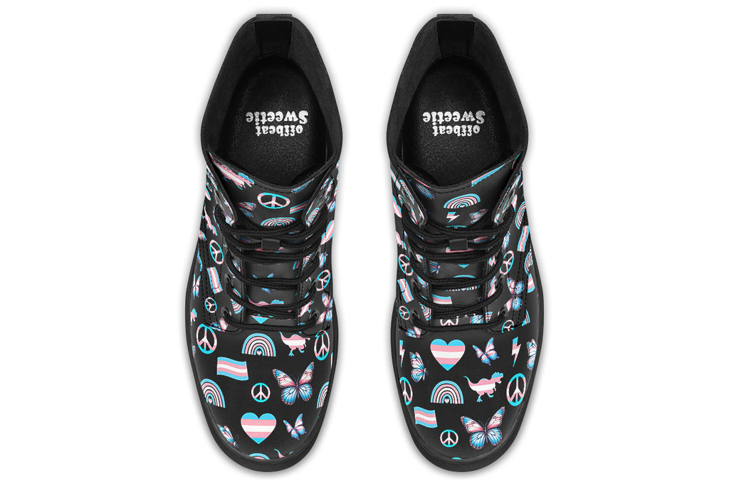 Black boots featuring a pattern of various icons in the trans flag colours, such as hearts, rainbows, peace signs, flags, butterflies and dinosaurs.
