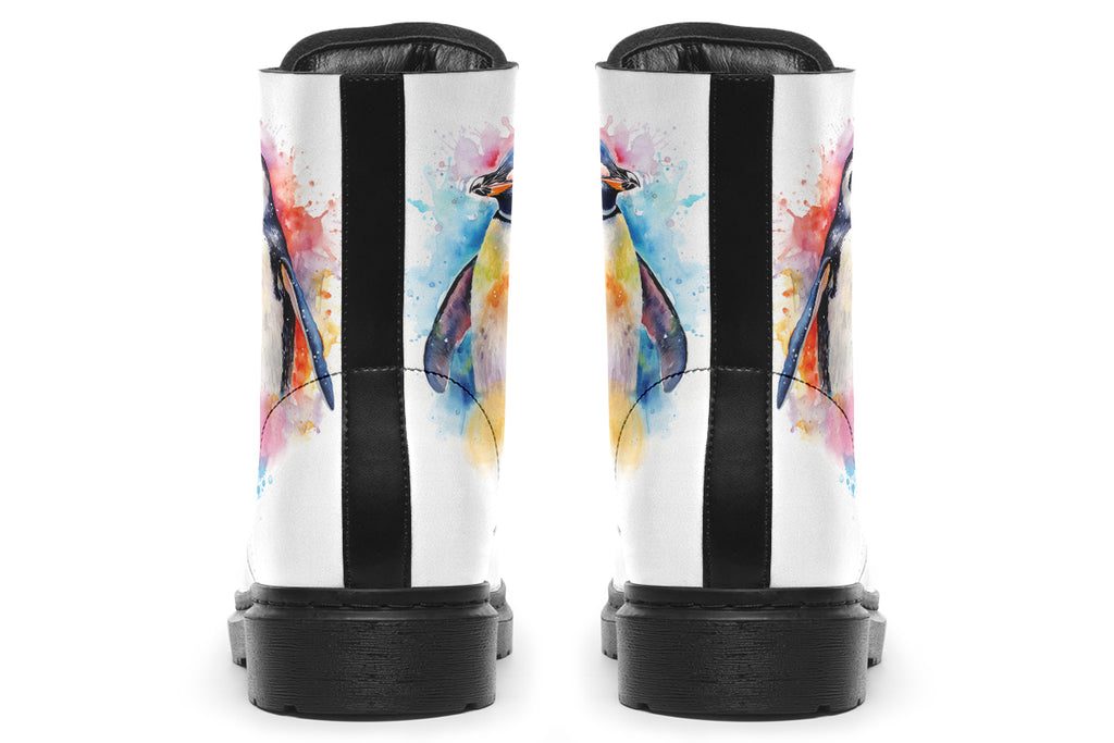 White boots with an image of a penguin on the sides, in the style of a watercolour painting with various colours splashed behind the penguin and on the toes and tongue of the boots