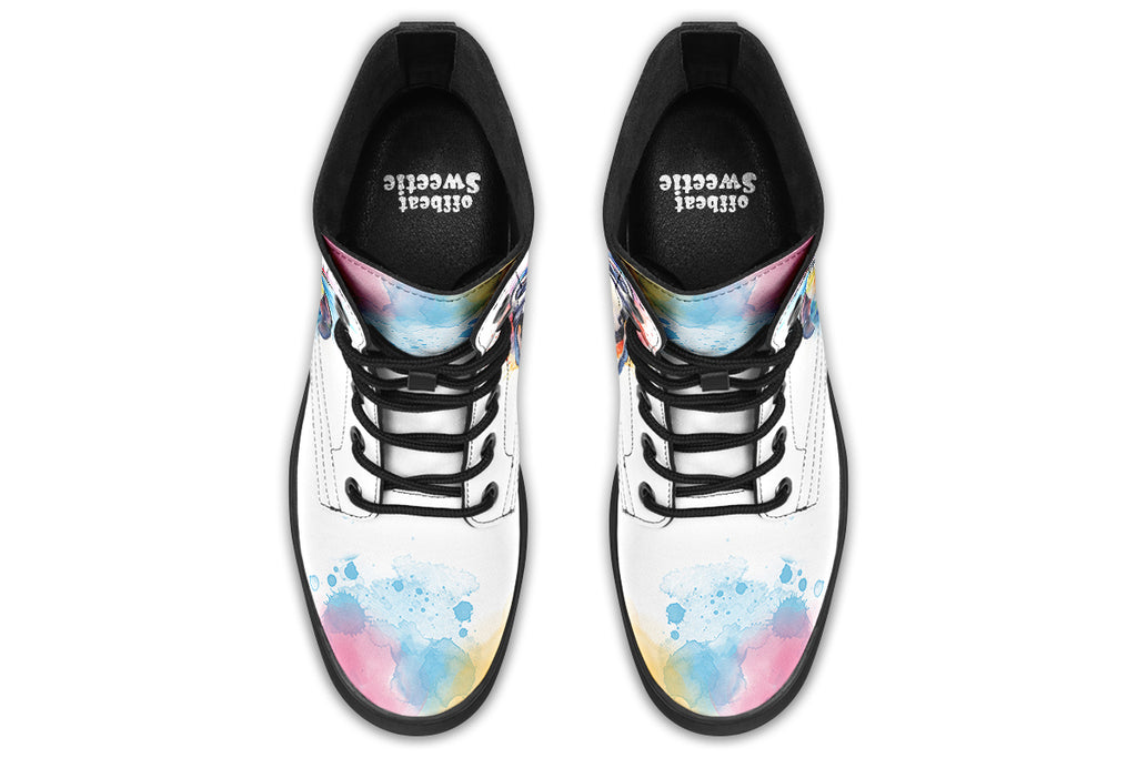 White boots with an image of a penguin on the sides, in the style of a watercolour painting with various colours splashed behind the penguin and on the toes and tongue of the boots