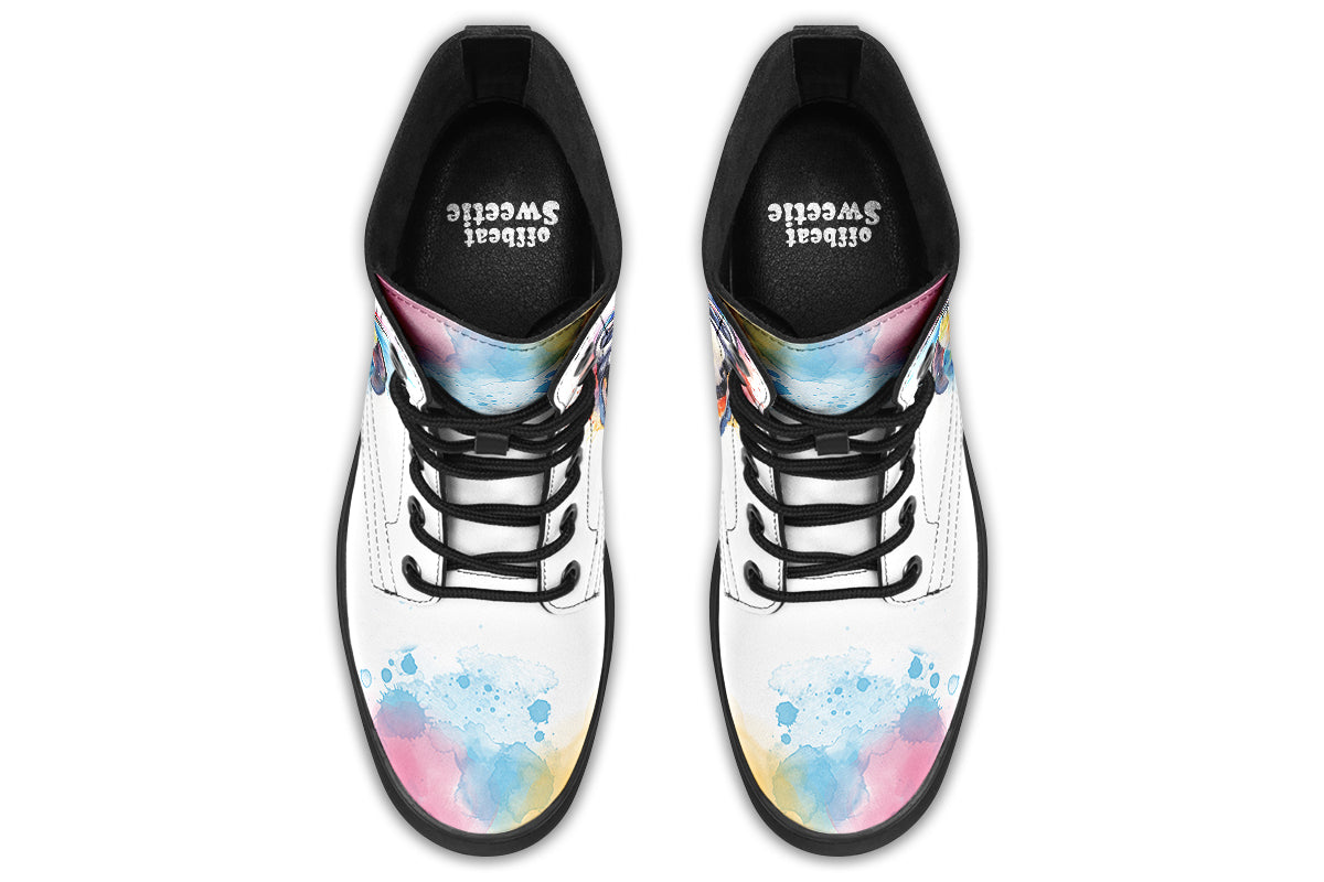 White boots with an image of a penguin on the sides, in the style of a watercolour painting with various colours splashed behind the penguin and on the toes and tongue of the boots