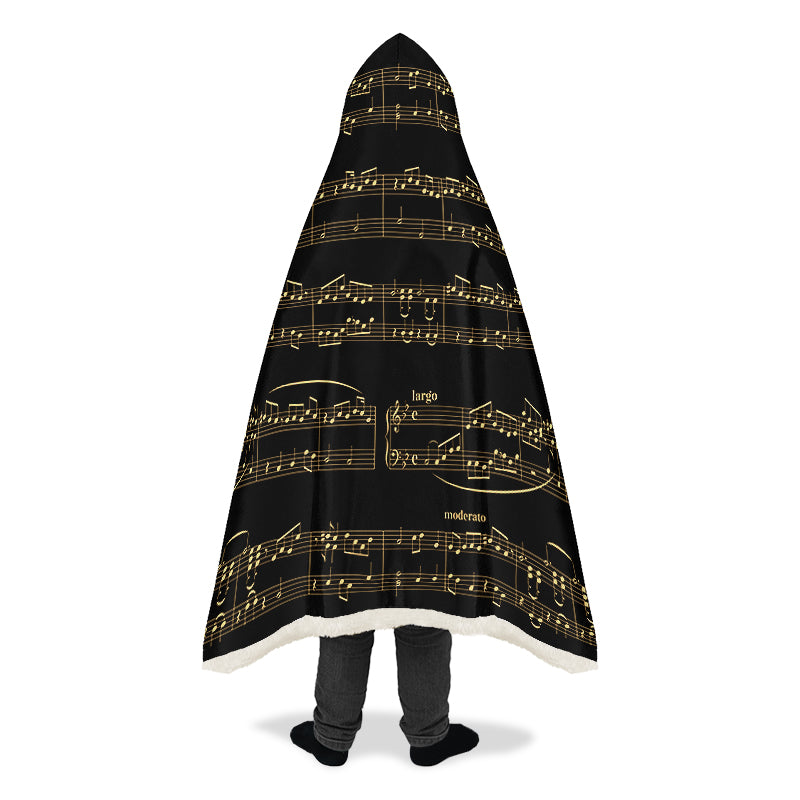 Person wearing a black hooded blanket with gold musical notes.