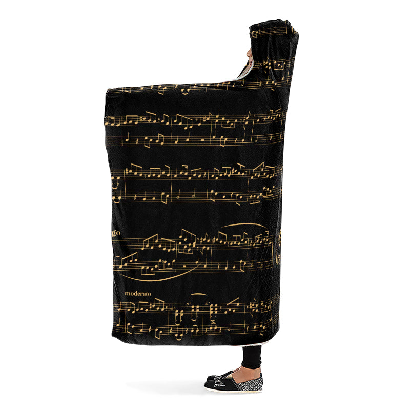 Side view of a person holding a hooded blanket with gold musical notes on black background.