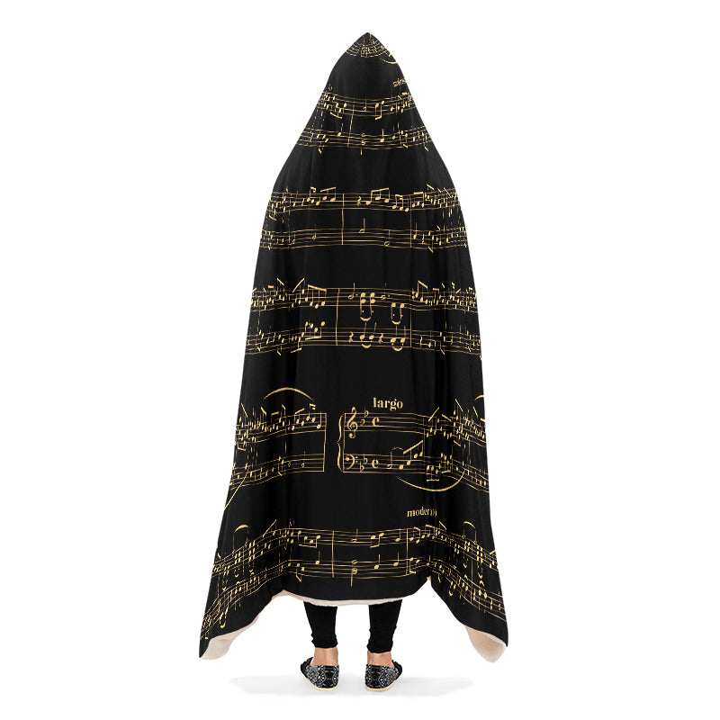 Hooded blanket with gold musical notes on black background, draped over a person.