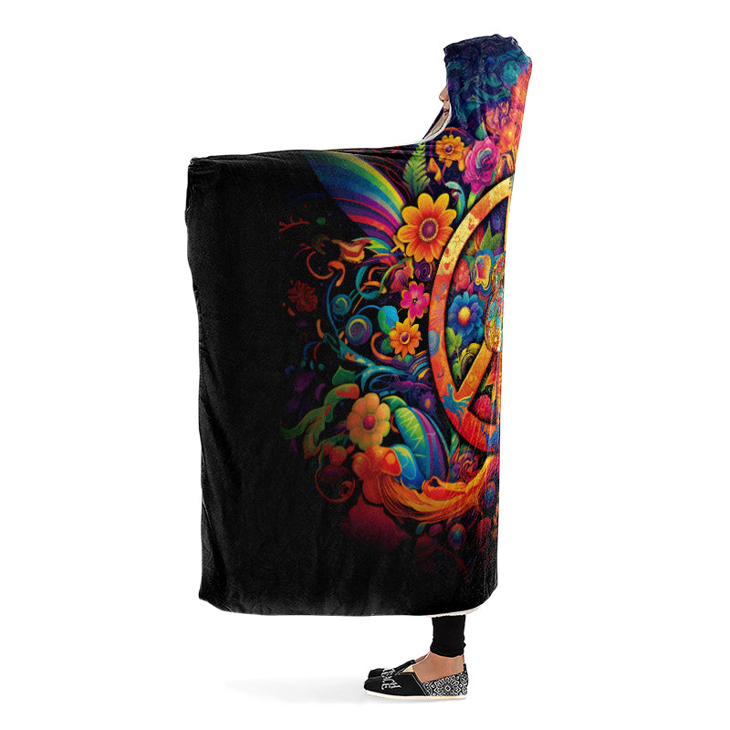 Colorful hooded blanket with peace symbol, guitar and floral designs on a black background. Side view.