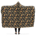 Hooded blanket with a retro-inspired paisley pattern in brown, green and burnt orange.