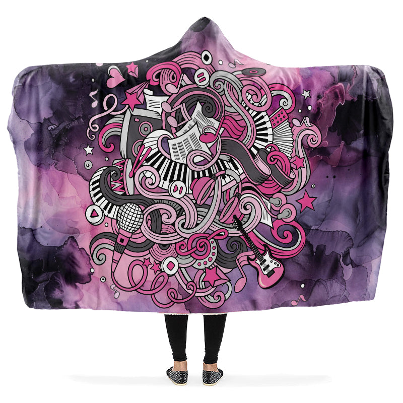 Hooded blanket with a colorful design of music notes, guitars, sheet music etc on a purple and pink gradient background.