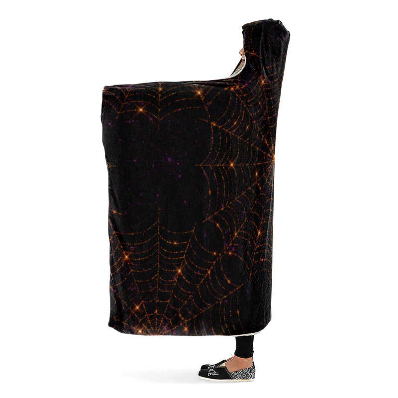 Black hooded blanket with spider web pattern worn by a person. Side view.