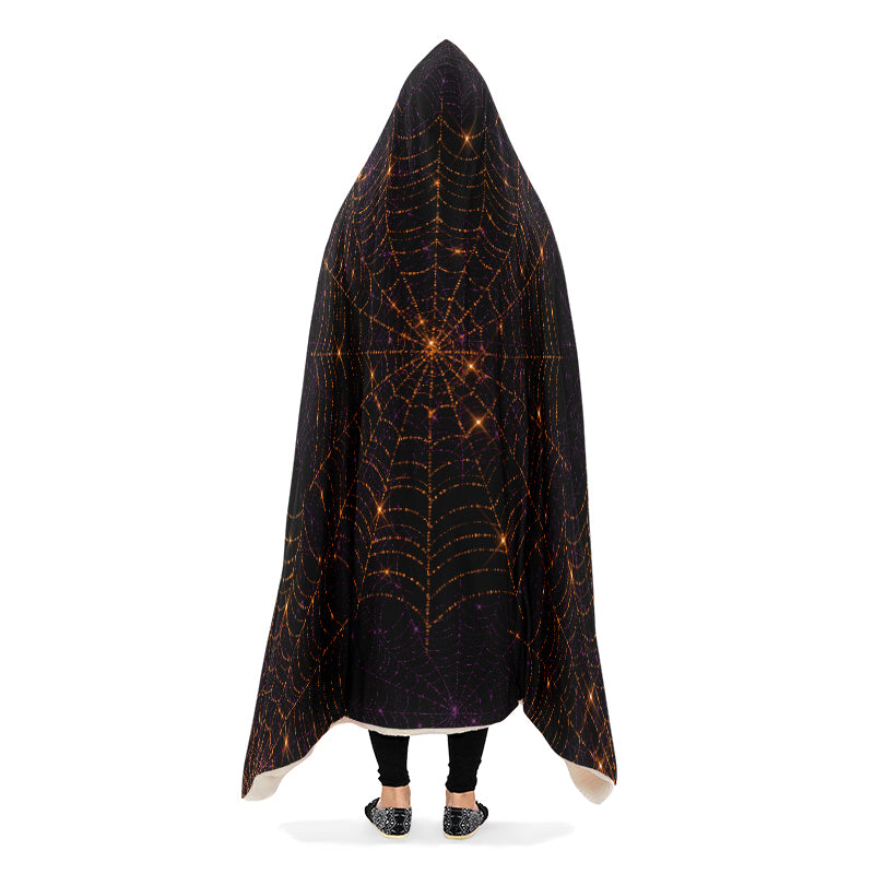 Person wearing a black hooded blanket with bronze spider web pattern.