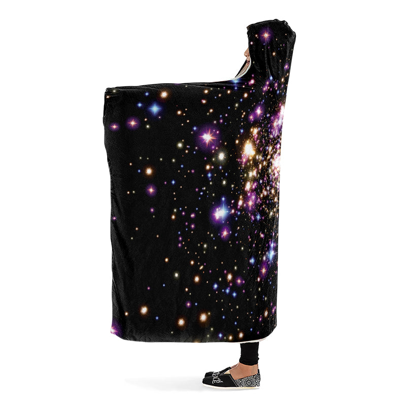 Black hooded blanket with galaxy design worn by a person with arms outstretched. Side view.
