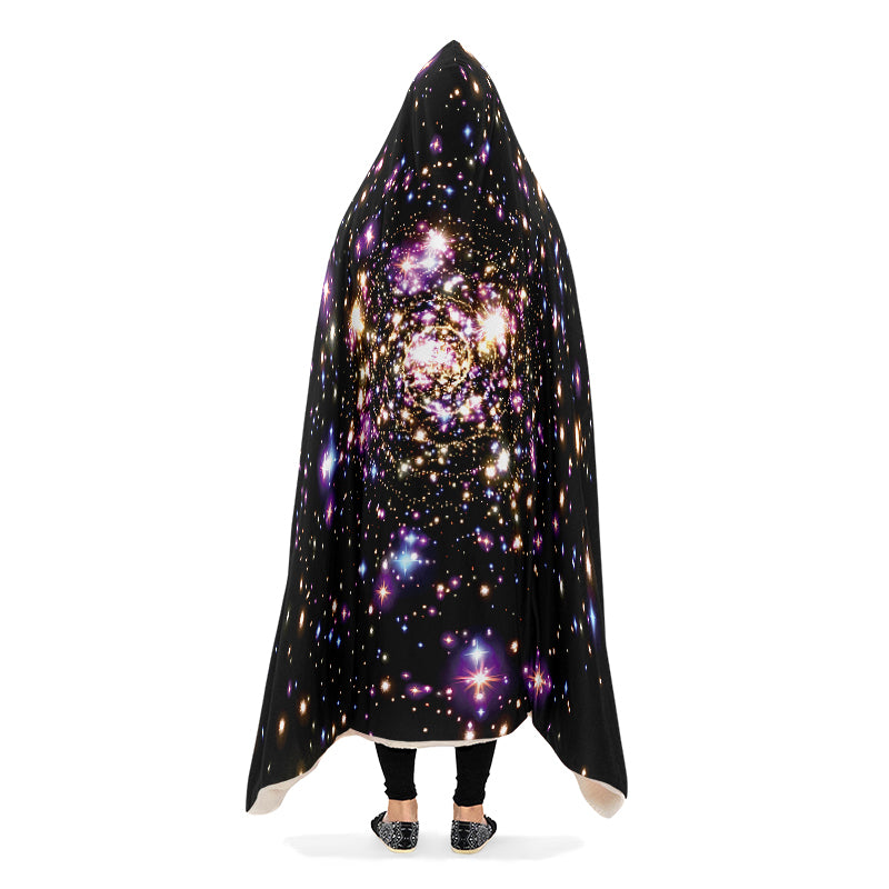 Person wearing black hooded blanket with galaxy design, arms down.