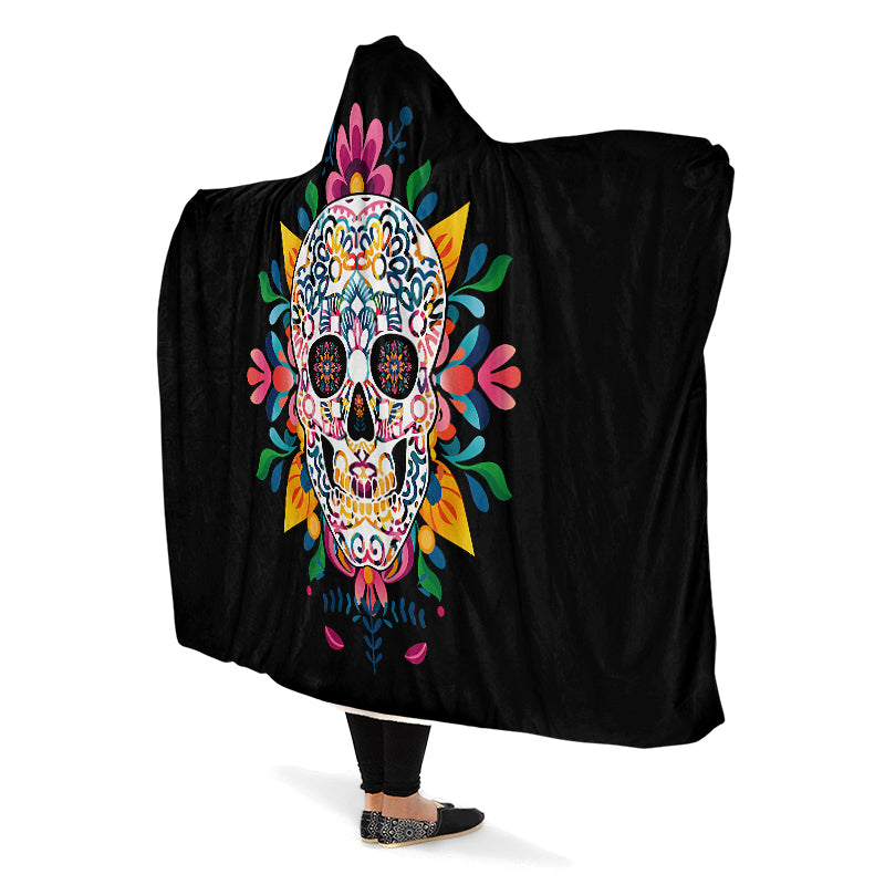 Black hooded blanket with a colorful skull design, being worn by a person with arms outstretched.