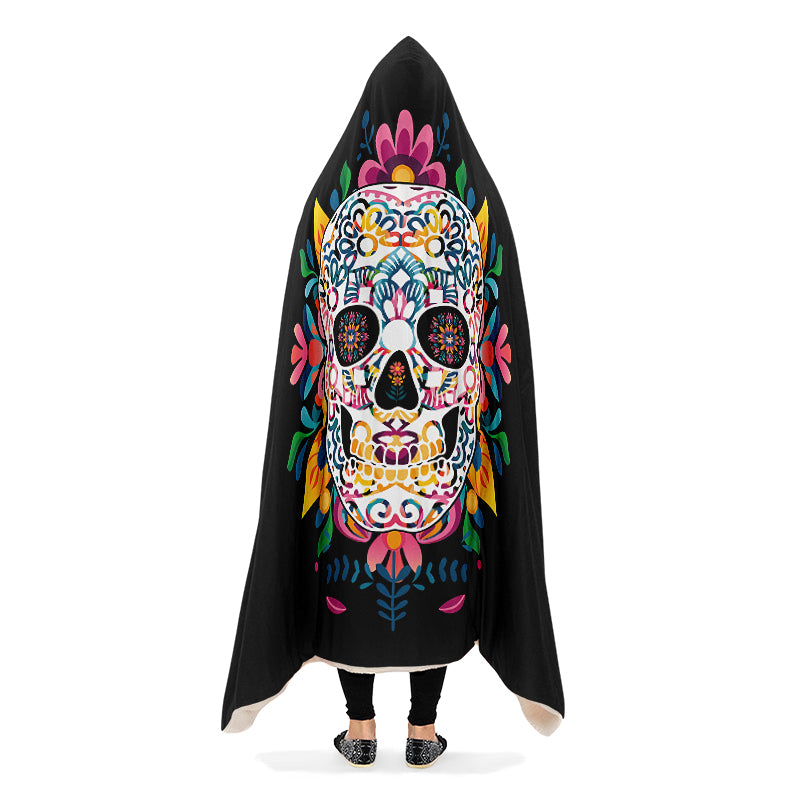 Black hooded blanket with a colorful skull design, being worn by a person with arms down.