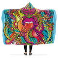 Colorful hooded blanket with a psychedelic design featuring guitars, flowers, and lips with the tongue sticking out. 