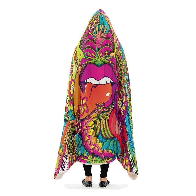 Colorful hooded blanket with a psychedelic design featuring guitars, flowers, and lips with the tongue sticking out. The blanket is being worn by a person with their arms down.