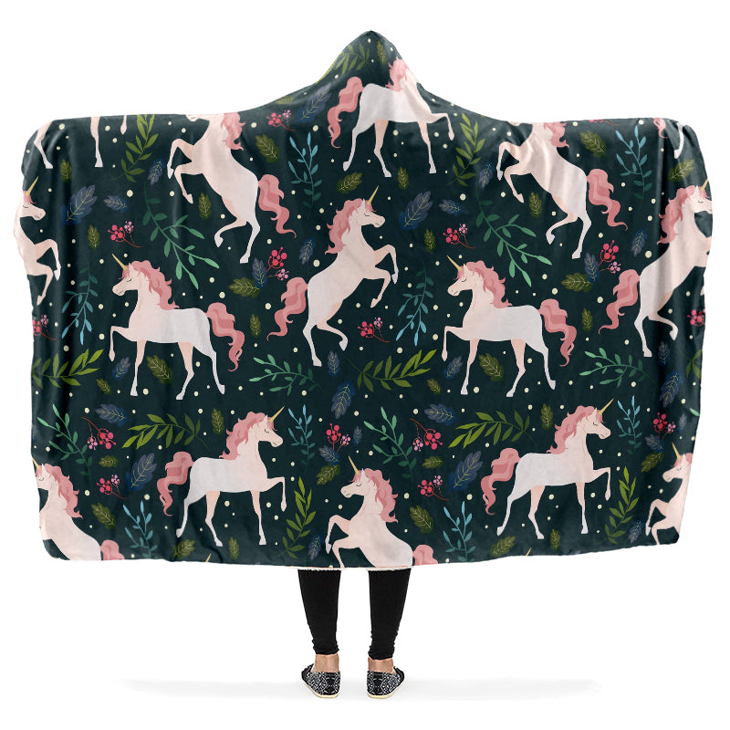Hooded blanket with white and pink unicorn and leaves pattern on a dark green background.