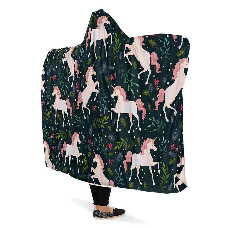 Hooded blanket with white and pink unicorn and leaves pattern on a dark green background.