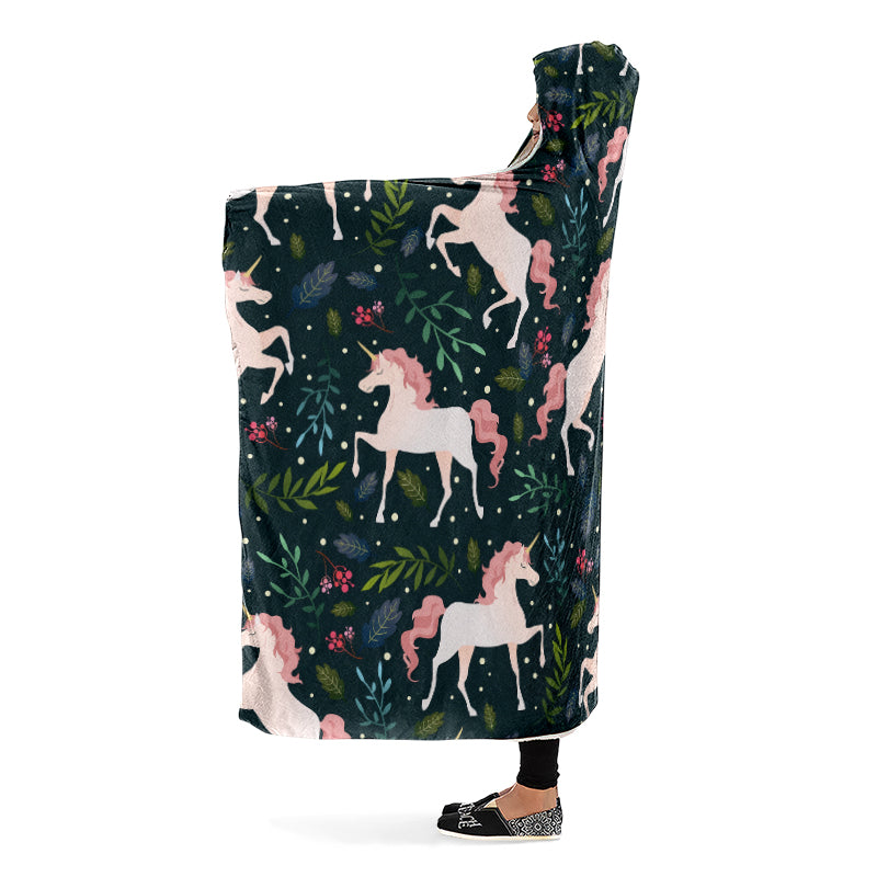 Hooded blanket with white and pink unicorn and leaves pattern on a dark green background. Side view.