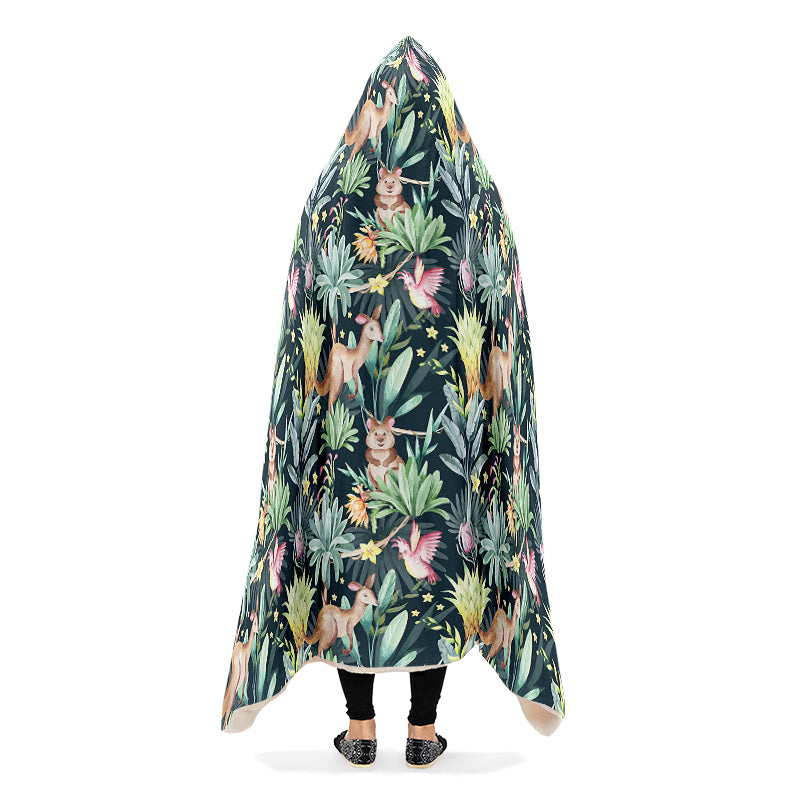 Person wearing a hooded blanket with an Australian animal pattern on a dark green background. The animals are kangaroos, quokkas and cockatoos.